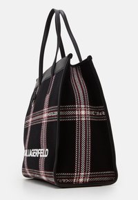 Svart rutigt tote bag med läderdetaljer; har ett rutigt mönster i röd och vit, hållbara handtag och en framträdande logotyp på sidan.