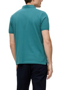Teal-polo paita, jossa on lyhyet hihat, pehmeästä puuvillasta valmistettu, klassinen kaulus, sivuaukot ja yksinkertainen pinta. Kuvattuna takaa.