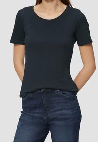 Korte mouwen, rondhals T-shirt in donker marineblauw katoenblend, gladde textuur, gecombineerd met donkerblauwe spijkerbroeken met zakken aan de voorkant.