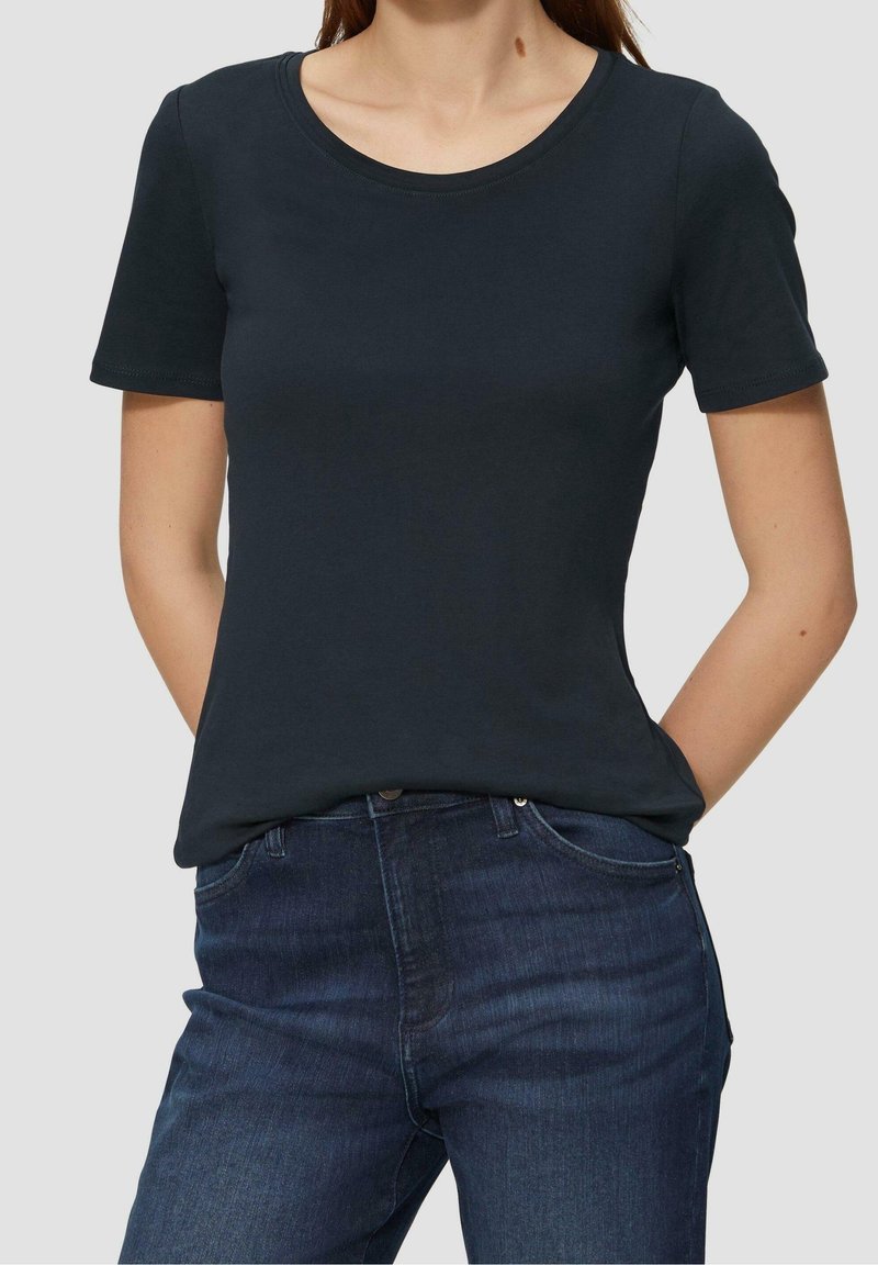 Korte mouwen, rondhals T-shirt in donker marineblauw katoenblend, gladde textuur, gecombineerd met donkerblauwe spijkerbroeken met zakken aan de voorkant.