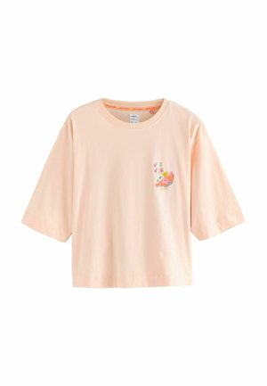 Lyse ferskenfarvet t-shirt med korte ærmer og en lille farverig fugl og blomsterbroderi på venstre bryst.