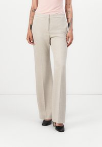 Hellbeige weite Hosen aus strukturiertem Stoff, mit hoher Taille und geradem Schnitt, kombiniert mit schwarzen High Heels.