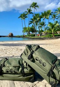 Borse da viaggio a duffel verdi con hardware nero, due ampi scomparti e caratteristiche con ruote. Loghi e dettagli lungo la parte anteriore.