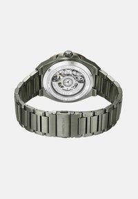 Zilveren roestvrijstalen horloge met een gepolijste afwerking, een heldere achterkant die de werking toont, en een stevige armbandontwerp.