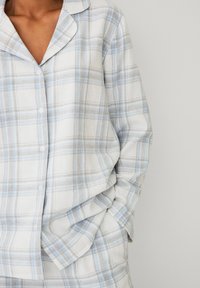 Pyjama-set met een knoopsluiting aan de bovenkant in lichtgrijs en blauw geruit patroon, zachte stof, ontspannen pasvorm en een klassiek kraagontwerp.