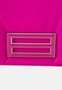 Borsa in nylon rosa con un accento hardware rettangolare lucido rosa, caratterizzato da due ritagli paralleli e un bordo argento. Texture liscia.
