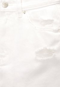 White denim jeans featuring distressed detailing with frayed edges, metal button closure, and standard five-pocket design.