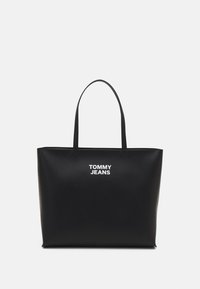 Svart tote-väska i syntetmaterial, med en strukturerad design, två handtag och vit "TOMMY JEANS"-logotyp på framsidan.