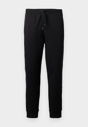 Calças de jogging pretas feitas de um tecido macio, com uma cintura elástica e cordão. Apresentam pernas ajustadas com punhos em ribana.