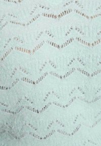 Maglione verde menta chiaro con motivo a zigzag, realizzato in un morbido tessuto testurizzato con un design a maglia aperta.