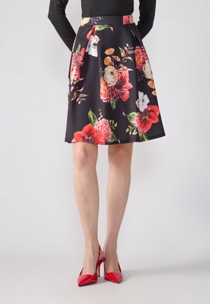 Black A-line skirt with large red, pink, and white floral patterns, worn with red high heels and a black long-sleeve top.
