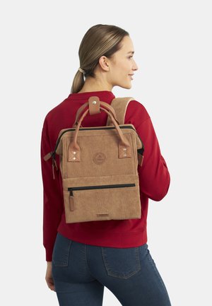 Brown corduroy backpack with leather accents, multiple pockets, top handles, and adjustable straps. Clean lines and structured design.