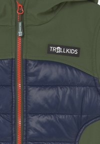 Zielono-granatowa kurtka o pikowanej strukturze, z czerwoną zamkiem błyskawicznym i czarną metką "TROLLKIDS". Wykonana z trwałych materiałów przeznaczonych do noszenia na świeżym powietrzu.