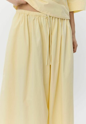 Gaiši dzeltena, viegla auduma svārki ar elastīgu jostasvietu un aukliņu. Aprīkoti ar mīkstām krokojumiem, kas veido vaļīgu, atslābinātu siluetu.