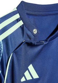Donkerblauw sportshirt met mintgroene accenten, een drukknoopsluiting en textuurstof met een prominente logo.