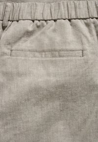 Pantaloni in lino grigio chiaro con vita elasticizzata e una singola tasca sul retro. Il tessuto ha una finitura texture.