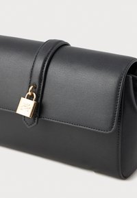 Czarna skórzana torebka kopertowa z klapką i złotym zapięciem w formie kłódki na pętlowym pasku.