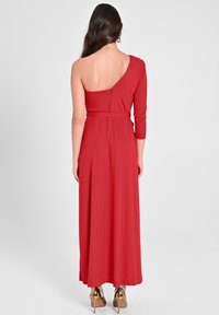 Rotes, einseitiges Maxikleid mit taillierter Passform, fließendem Rock und glattem Stoffgefühl. Mit tiefem Rückenausschnitt und einem langen Ärmel.