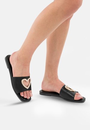 Infradito neri con un luccicante cuore dorato accentato da strass, design aperto sulla punta e suola piatta in gomma.
