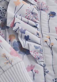 Tissu à motif floral présentant des fleurs pastel de couleur rose, bleue et jaune sur un fond blanc, avec une texture froncée et des accents côtelés.