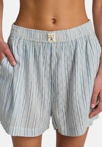 Shorts bleu clair en tissu texturé avec des rayures verticales bleu clair et crème. Comprend une ceinture froncée et des poches latérales.