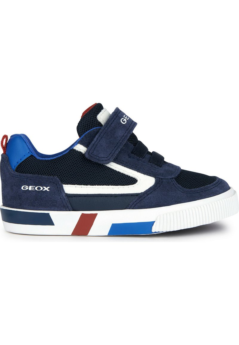 Zapatillas de deporte azul marino con parte superior de malla y gamuza, acentos en blanco, rayas rojas y azules en la suela, y correa de velcro para un ajuste seguro.