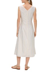 Robe sans manches avec dos en V en tissu bleu clair avec des rayures dorées. Forme évasée avec une longueur intermédiaire de l'ourlet et une texture lisse.