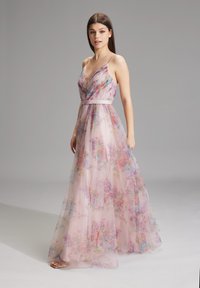 Vaatteet, joissa on lennokkaita kukkakuoseja, läpinäkyvää vaaleanpunaista kangasta, syvä V-kaula-aukko, ohuet olkaimet ja yhteensopiva vyö, joka korostaa siluettia.