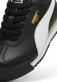 Must must rehvi musta nahk kingad valgete aktsentidega ja tekstuuriga pinnaga. Omab musti paelu ja kuldset logo, millel on külje peal kirjas "PUMA ROMA".