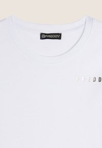 T-shirt bianca in cotone con scollo rotondo e maniche corte, con il logo metallic o argento "FREDDY" sul lato sinistro del petto.