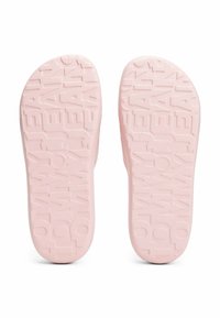 Suole di scarpe in gomma rosa con marchio impresso e motivi testurizzati per una buona presa, con una finitura liscia e bordi arrotondati.