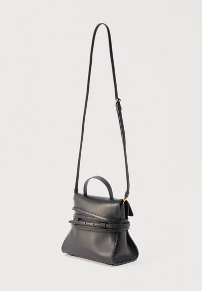 Μαύρη δερμάτινη τσάντα χειρός με δομημένο σχήμα, επάνω λαβή και μακρύ ρυθμιζόμενο ιμάντα ώμου, παρουσιάζεται σε απλό ανοιχτό φόντο.