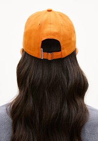 Verstellbare Baseballcap aus leuchtend orangefarbenem Stoff mit runder Oberseite, Hinterverschlussschnalle und einem Logotag an der Seite.