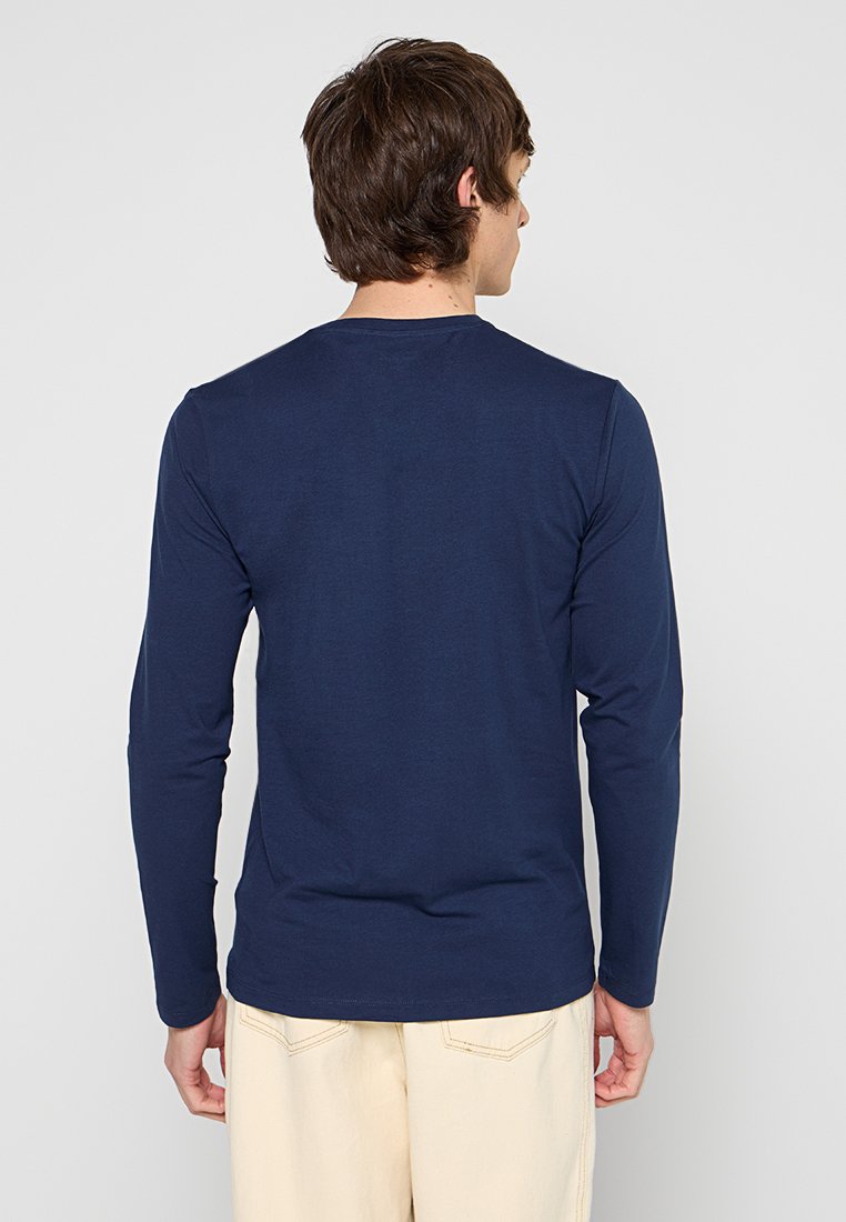 Camisa de manga larga en tejido de algodón color marino. Presenta un cuello redondo y un diseño ajustado con textura suave. Sin patrones ni acentos visibles.