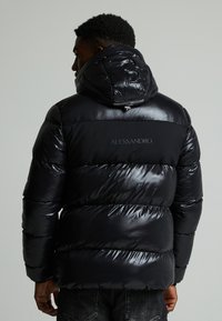 Schwarze Pufferjacke mit glanzbeschichteter Oberfläche, verstellbare Kapuze und horizontalem Steppdesign. Verfügt über ein Logodetail im oberen Rückenbereich.