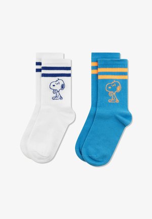 Deux paires de chaussettes montantes, l'une blanche avec des rayures bleu marine et Snoopy, l'autre bleue avec des rayures orange et Snoopy, posées à plat sur un fond blanc.