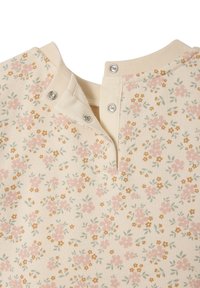 Helles Creme-Stoff mit floralem Muster in rosa und gelben Blumen; verfügt über einen Druckknopfverschluss am Hals. Weiches, strukturiertes Material.