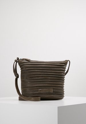 Sac bandoulière en cuir brun foncé avec des rainures horizontales, une sangle réglable et une fermeture éclair sur le dessus, posé sur une surface blanche.