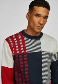 Pullover-Pullover mit einem geometrischen Muster in Rot, Marineblau und Grau. Hergestellt aus Strickstoff mit gerippten Ärmelbündchen und Halsausschnitt.