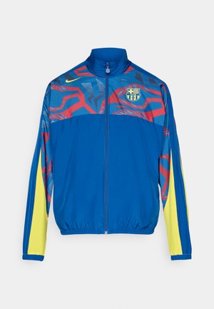 Modrá športová bunda s červenými a žltými akcentmi, s vysokým golierom, predným zipsom a logom FC Barcelona na hrudi.