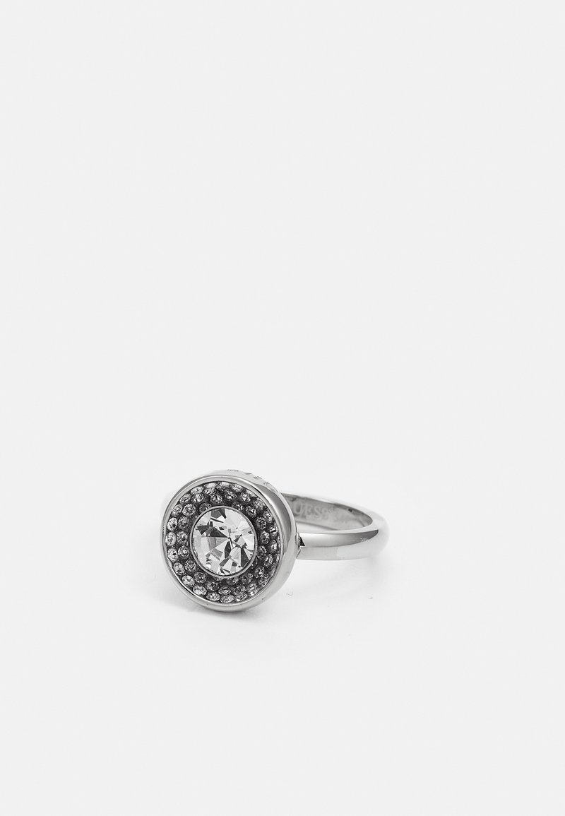 Bague en argent avec une grande pierre précieuse claire au centre entourée de petites pierres claires dans un sertissage circulaire sur un fond blanc uni.
