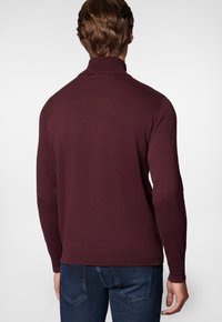 Bordowy sweter z golfem, z żeberkowym kołnierzem i mankietami, wykonany z dzianiny, o dopasowanym kroju i klasycznej sylwetce.