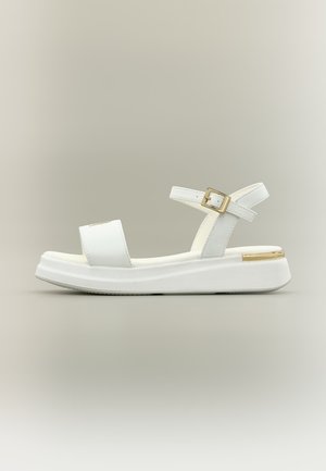 White platform sandal with ankle strap, gold buckle, and gold detail on the sole's back, shown against a plain neutral background.