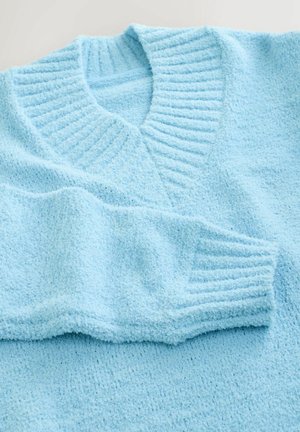 Lyseblå sweater lavet af struktureret stof, med en ribbet V-hals og manchetter. Blødt, hyggeligt udseende med en let løs pasform.