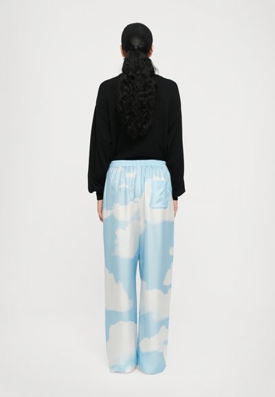 Hellblaue Hosen mit weißen Wolkenmustern, elastischem Bund und einer Gesäßtasche. Das Material wirkt glatt und leicht fließend.