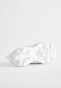 Weiße Sneaker-Sohle mit strukturiertem Gummi, gekennzeichnet durch ein geschwungenes Design und markante Profilmuster für Grip und Traktion. Sauberes und minimalistisches Erscheinungsbild.