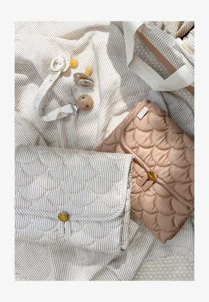 Dos cambiadores de bebé acolchados en rayas beige y blancas con cierres de botón dorado, dos chupetes y un clip para chupete sobre tela.