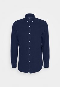 Marinblå långärmad skjorta med knappar och krage, med vita knappar och ett litet emblem på bröstet. Tillverkad av mjukt bomullsmaterial.