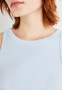 Lys blå ribbet tanktop med rund halsutskjæring og subtil tekstur, med en tettsittende design og rene søm-detaljer.