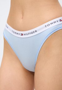 Φωτεινό γαλάζιο βαμβακερό εσώρουχο με λευκή μέση που φέρει το λογότυπο Tommy Hilfiger, φορεμένο στη μέση και στους γοφούς.